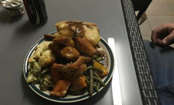 a plate of food on a dining table , consisting of a variety of vegetables and meat at Oasis Motel