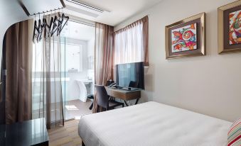 a hotel room with a bed , desk , and tv , as well as a bathroom door and window at 57Hotel