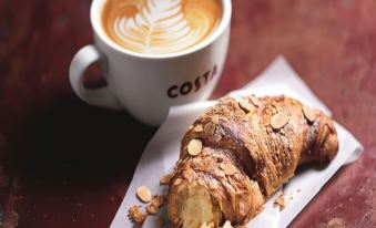 a cup of coffee and a croissant are placed on a table , with a croissant on the side at Days Inn by Wyndham Sutton Scotney South