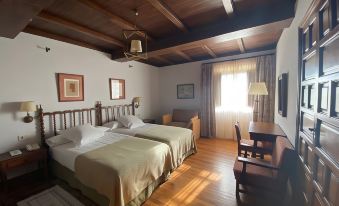 a bedroom with wooden floors , a bed with green sheets , and a desk near the window at Parador de Verin