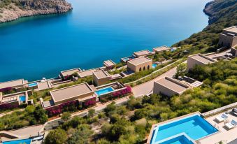 a resort with a pool and multiple buildings is nestled near the ocean , providing a serene view of the surrounding landscape at Daios Cove