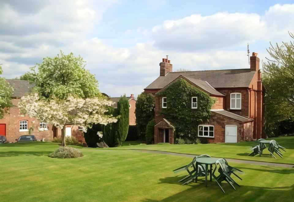 a large brick house with a green lawn and picnic table in front of it at Ash Farm Country House