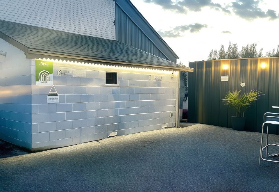 a small white house with a black awning , located next to a brick patio and surrounded by grass at Lovely