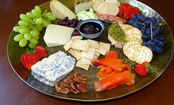 a large platter filled with a variety of appetizers , including cheese , crackers , and fruit , placed on a dining table at Oyster Cove Chalet