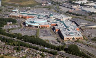 aerial view of a large shopping mall with multiple parking garages , surrounded by other buildings and greenery at The Ascott