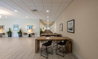 a modern office space with white walls , wooden floors , and black tables arranged for meetings or gatherings at Penn Harris Hotel Harrisburg, Trademark by Wyndham