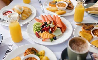 a table is set with plates of fruit and other dishes , along with orange juice and coffee at Paradise Country Farmstay