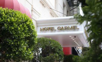"a white building with a sign that reads "" hotel carmel "" prominently displayed on the front of the building" at Hotel Carmel Santa Monica