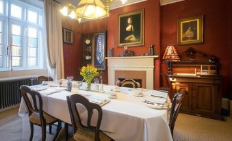 a dining room with a table set for a meal , surrounded by chairs and a fireplace at Blaisdon House B&B