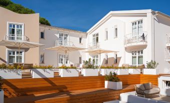 a large white building with multiple balconies and an outdoor dining area featuring potted plants and wooden furniture at La Coluccia