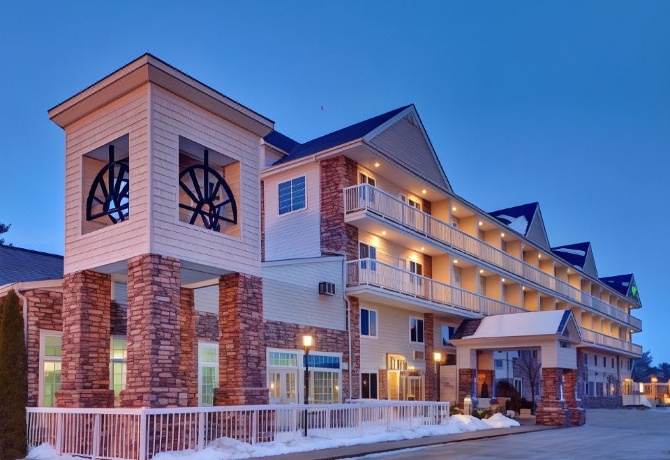 a two - story building with a clock tower on the side and snow on the ground at Holiday Inn Express Mackinaw City