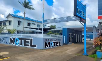 "a blue motel with a sign that reads "" black narcissus motel "" prominently displayed on the building" at Black Marlin Motel