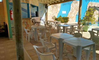 a room with white plastic chairs and tables , a blue mural on the wall , and a potted plant at Hotel del Sol
