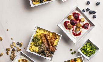a variety of colorful bowls filled with different types of food , such as fruits , vegetables , and nuts , placed on a white table at Hyatt Place Pittsburgh Airport/Robinson Mall
