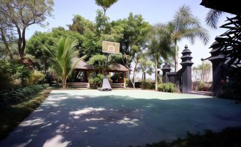 a basketball court surrounded by trees and a gazebo , with a person playing basketball on the court at Griya Gendhis Saraswati