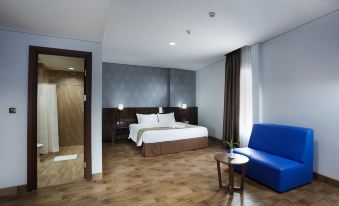 a modern hotel room with a wooden floor , white beddings , and blue accents , including a blue couch and a blue chair at Horison Express Sentani