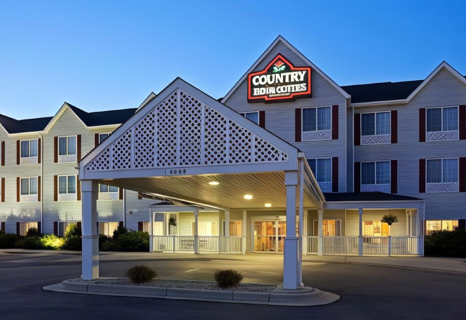 a holiday inn express hotel with its sign , lit up at night , and entrance to the building at Country Inn & Suites by Radisson, Watertown, SD