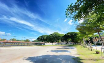 a large , empty parking lot with trees and a clear blue sky in the background at MaiHom Villa