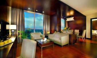 a modern living room with wooden floors , large windows offering views of the city , and comfortable seating arrangements at ASTON Purwokerto Hotel & Convention Center