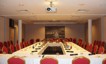 a large conference room with a long table and red chairs , set up for a meeting at Te Moana Tahiti Resort