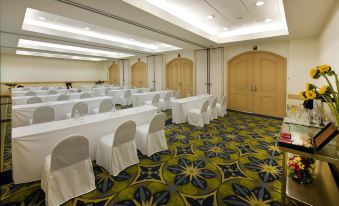 a conference room with tables and chairs , all covered in white tablecloths , is set up for a meeting at Quality Hotel Real Aeropuerto Santo Domingo