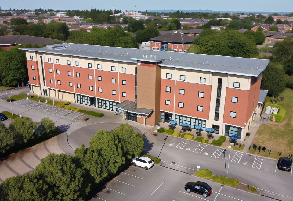 a large brick building with a parking lot in front of it , surrounded by trees and a car at Ramada Plaza by Wyndham Wrexham