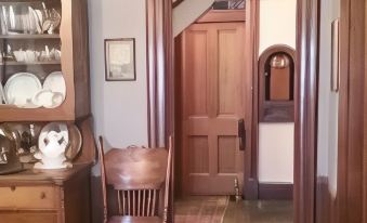 a wooden dining room with a large wooden door , multiple pieces of furniture , and a dining table at Smithville Historical Museum and Inn