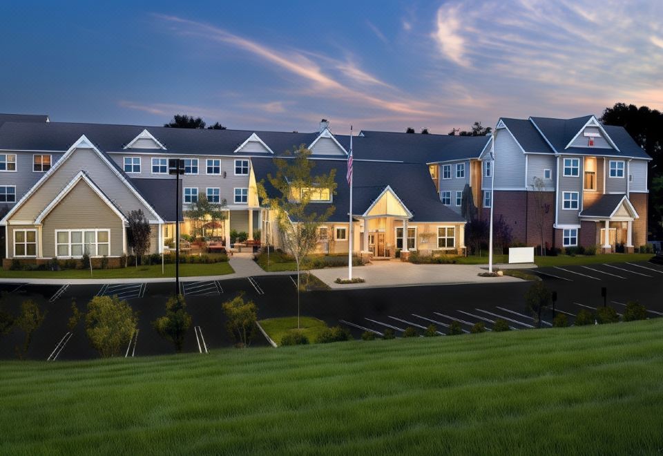 a modern , well - lit apartment building with multiple balconies and a parking lot in front of it at Residence Inn Bridgewater Branchburg