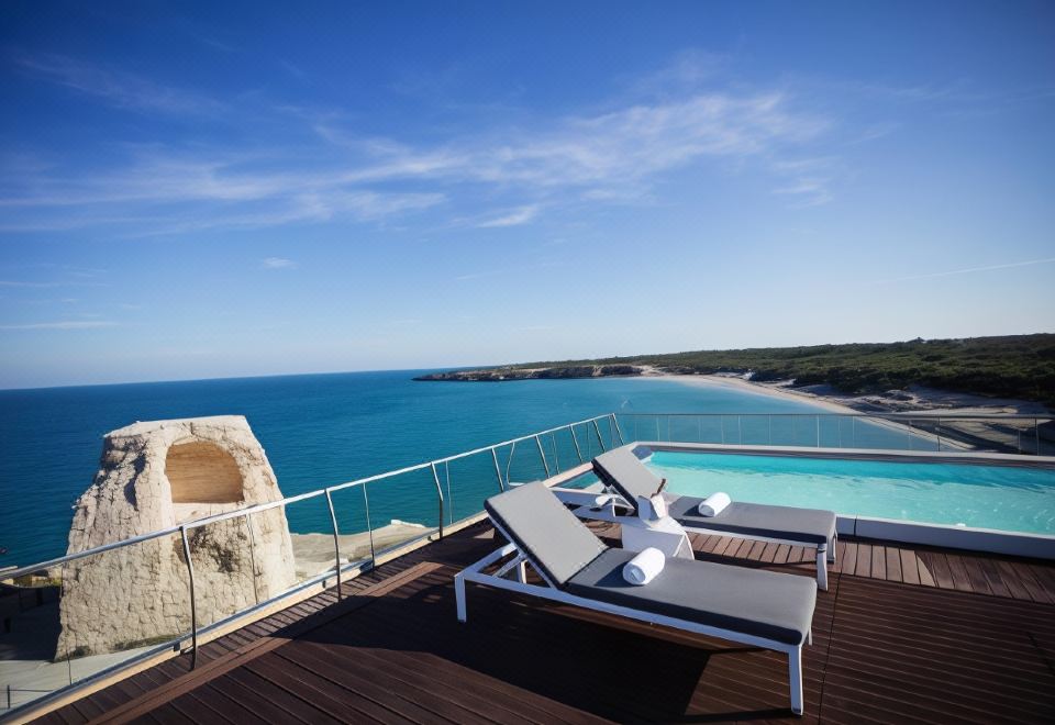 a wooden deck overlooking the ocean , with lounge chairs placed near the edge of the pool at Hotel Belvedere