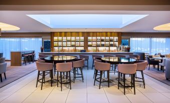 a modern restaurant with a bar area and several dining tables , all surrounded by chairs at Leonardo Hotel and Conference Venue Hinckley Island