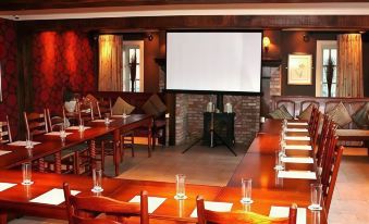 a large screen is set up in a room with wooden tables and chairs , along with vases of water at The Windmill Inn