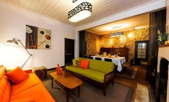 a living room with a green couch , wooden coffee table , and dining area with orange cushions at Inn Mahogany Creek