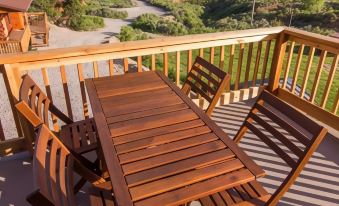 a wooden deck with a dining table and chairs , surrounded by lush greenery and a beautiful view of the countryside at Boulder Mountain Guest Ranch