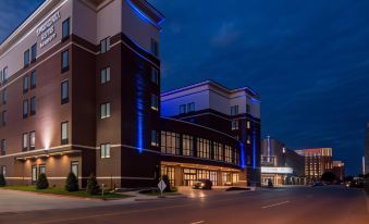 a modern hotel building at night , with its blue lights illuminating the exterior and cars parked outside at SpringHill Suites Oklahoma City Downtown/Bricktown