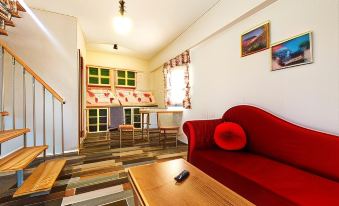 a cozy living room with a red couch , wooden coffee table , and television , as well as a dining area with chairs and a table at La Vida Hotel