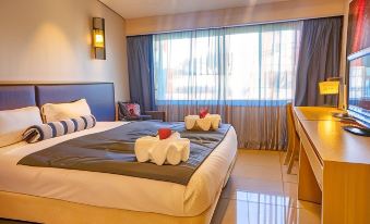 a hotel room with a double bed and a single bed , both covered with towels at Highlander Hotel