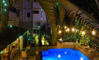 a swimming pool surrounded by palm trees at night , with lights illuminating the area around the pool at Casablanca
