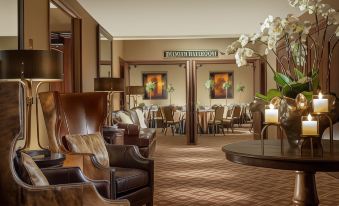 a spacious hotel lobby with wooden chairs and tables , an artwork on the wall , and large windows at The Lodge at Jackson Hole