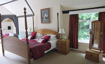 a bedroom with a four - poster bed , wooden furniture , and a window overlooking a forest at The Bentley Brook Inn