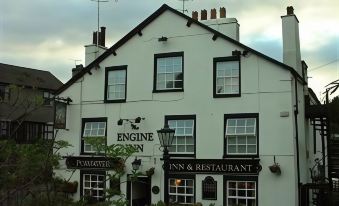 "a white building with black trim , featuring the name "" engine inn "" and a sign for other establishments" at The Engine Inn