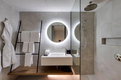 a modern bathroom with a white sink , mirror , and towels hanging on a rack , as well as a ladder leaning against the wall at Oval Hotel at Adelaide Oval, an EVT hotel