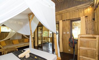 a large bed with white canopy and mosquito net in a room with wooden walls at Rinjani Beach Eco Resort