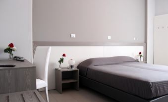 a modern bedroom with a white bed , grey walls , and a white chair near the bed at Hotel Savoia