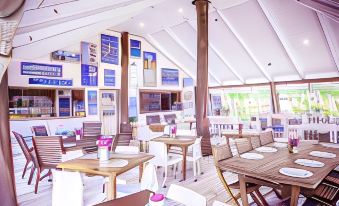 a large dining room with white tables and chairs , blue menus on the walls , and pink flowers at Le Life Resort