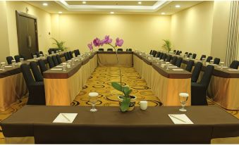 a long dining table set up for a meeting , with multiple chairs arranged around it at Merapi Merbabu Hotels Bekasi