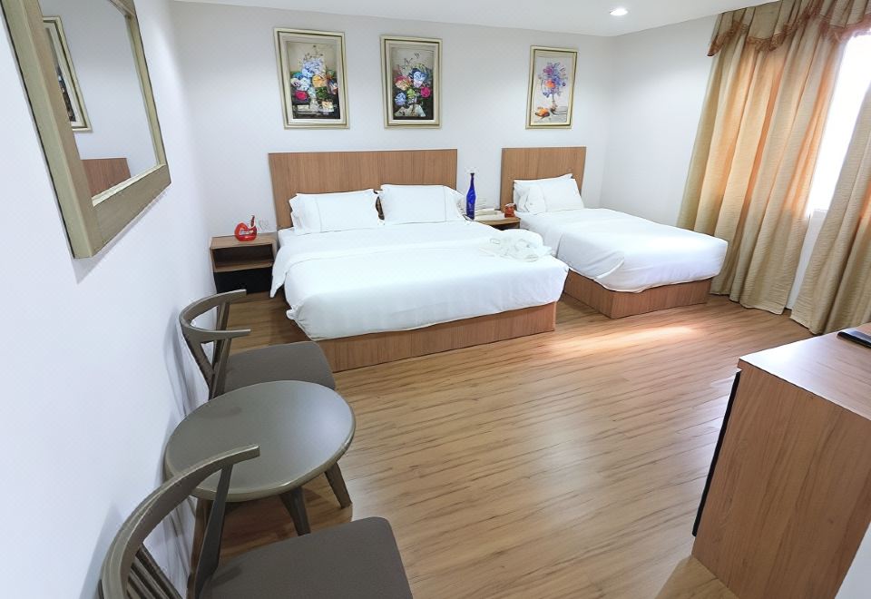 a hotel room with two beds , a chair , and chairs in various positions , including the foot of the bed and the door at Royale Hotel Batu Gajah