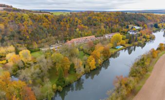 a large building is situated on the bank of a river surrounded by trees and autumn foliage at Club Wyndham Normandy