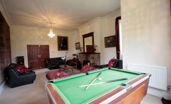 a large room with a pool table , couches , and a fireplace is shown in this image at Irton Hall