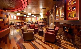 a modern lounge area with wooden floors , leather chairs , and red pendant lights , giving it an inviting atmosphere at Akwesasne Mohawk Casino Resort and Players Inn Hotel -Formerly Comfort Inn and Suites Hogansburg NY