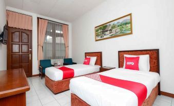 a modern hotel room with two beds , a window , and a painting on the wall at Super OYO Capital O 1644 Hotel Griya Kencana